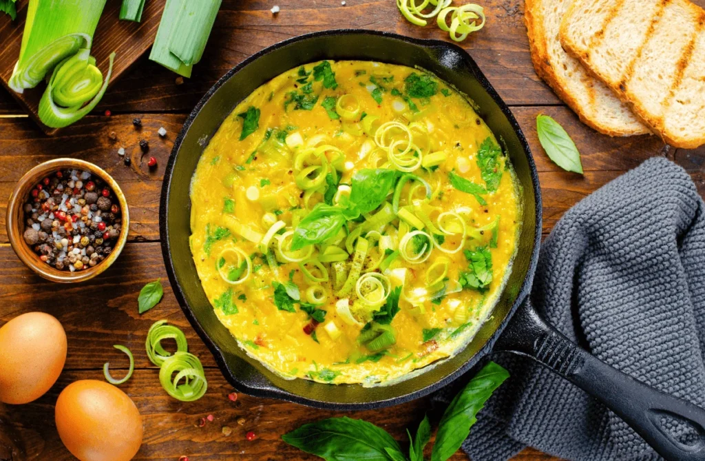  A non-stick pan with an omelette cooking, featuring melted cheese and fresh vegetables for a tasty omelette with cheese and vegetables.