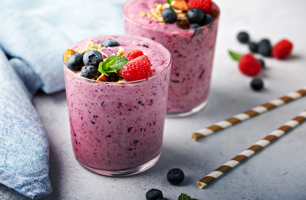 A berry smoothie with strawberries, blueberries, and raspberries, garnished with fresh berries and mint.