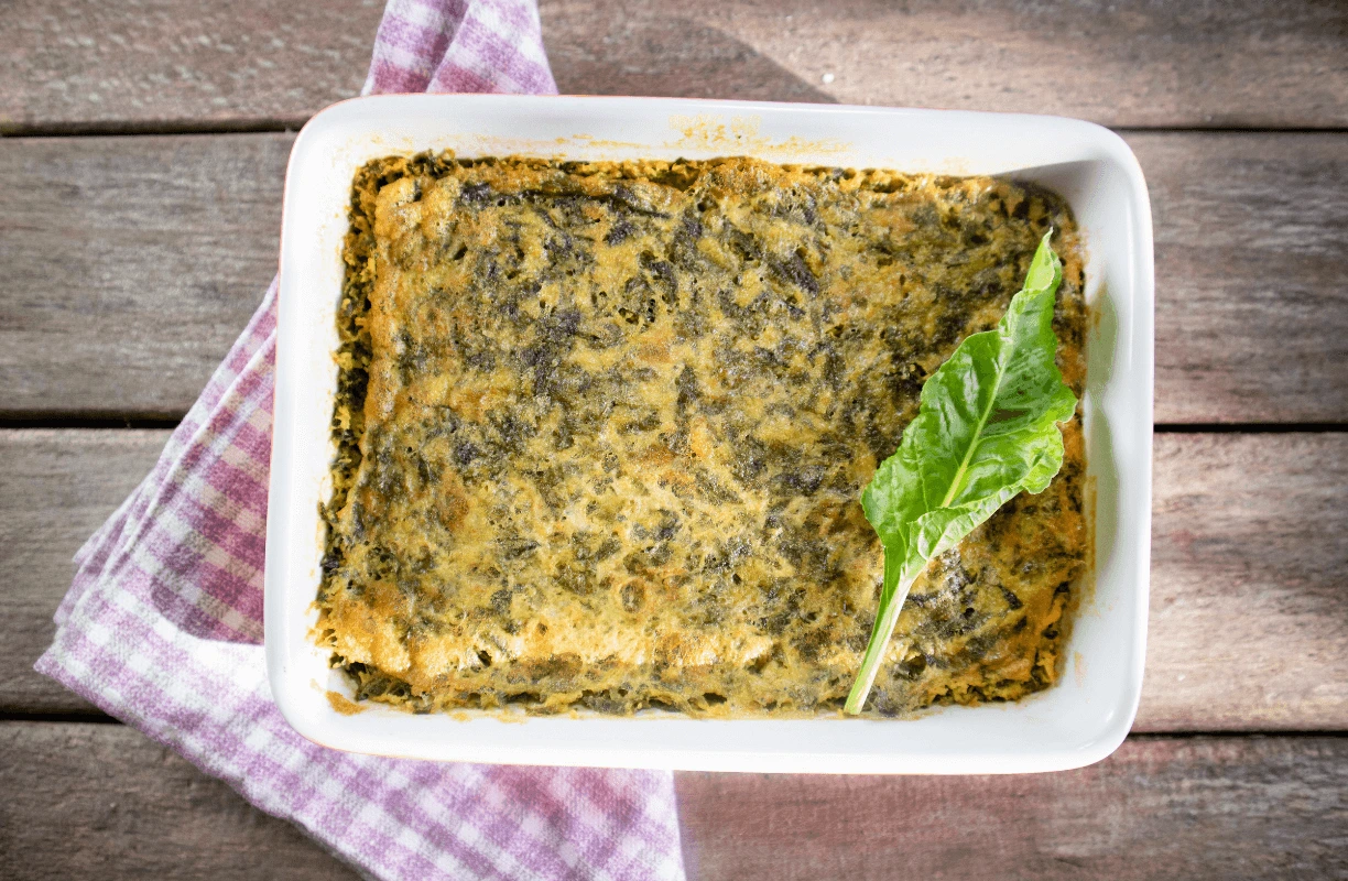 A baked egg-free omelette with fresh greens, served on a square dish with a purple checkered napkin.